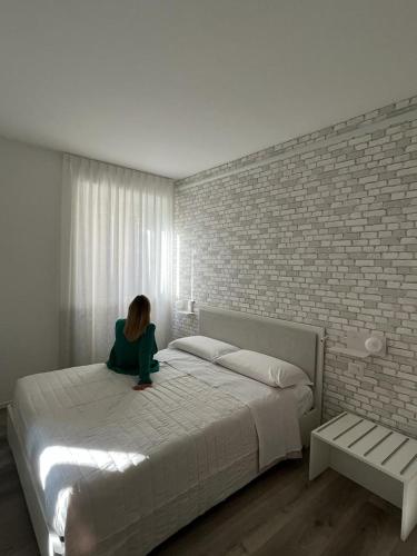 a woman sitting on a bed in a bedroom at Rosso Conero - Le Grotte Rooms & Apartments in Camerano