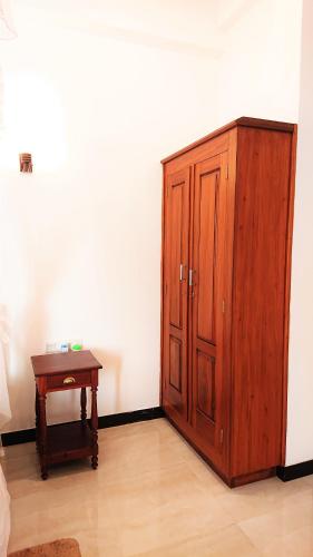 a wooden cabinet and a table in a room at Tropical Inn in Mirissa