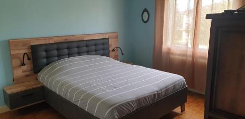 - un lit dans une chambre avec une tête de lit en bois dans l'établissement Maison chaleureuse, à Casseneuil