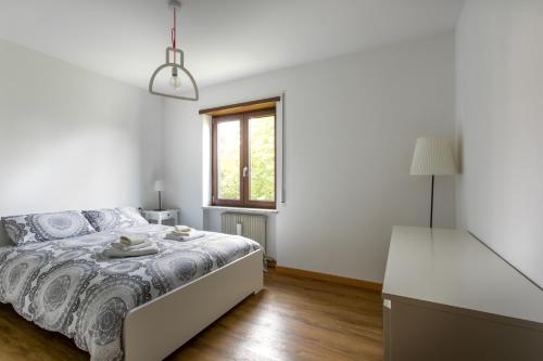 a white bedroom with a bed and a window at WoodenKey Asiago bicamere immerso nel verde in Asiago