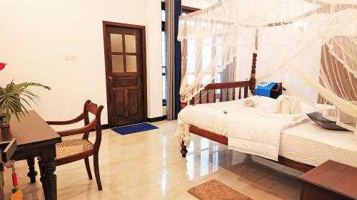a bedroom with a bed and a table and a desk at Tropical Inn in Mirissa