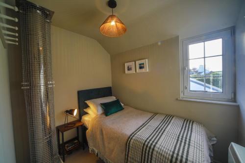 Habitación pequeña con cama y ventana en Bwthyn Gwyn, en Ederyn