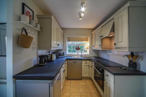 a kitchen with white cabinets and black counter tops at Bwthyn Gwyn in Ederyn