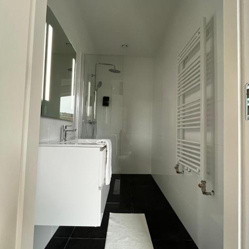 a white bathroom with a sink and a mirror at The Residence Apeldoorn in Apeldoorn