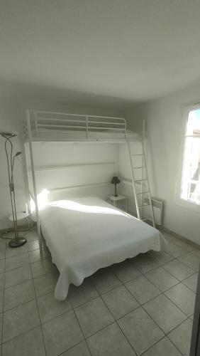 - une chambre avec un lit blanc et une échelle dans l'établissement Villa à deux pas de la cité médiévale dans une résidence très calme, à Aigues-Mortes