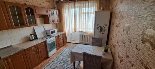 a kitchen with a table and a white refrigerator at Sweet Home 2 in Atyrau