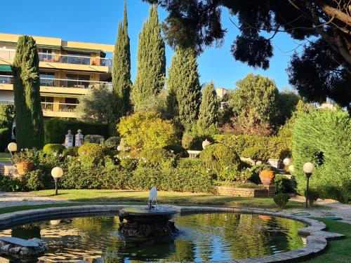 einen Brunnen in einem Garten mit einem Gebäude im Hintergrund in der Unterkunft Studio grande terrasse à 5 min de la mer in Nizza