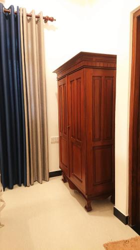 a wooden cabinet in a room next to a curtain at Tropical Inn in Mirissa