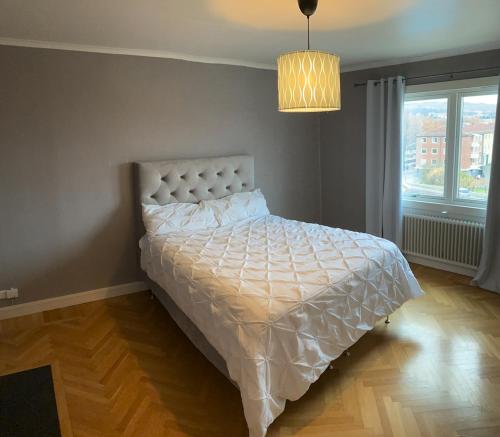 1 dormitorio con 1 cama con edredón blanco y ventana en Iris en Huskvarna