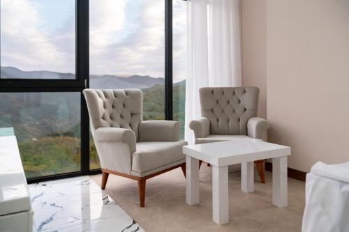 two chairs and a table in a room with windows at Chateau Milisi in Batumi