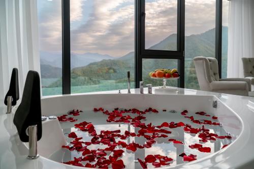 a bath tub filled with red flowers in front of a window at Chateau Milisi in Batumi
