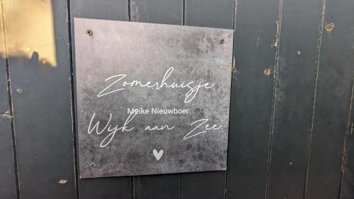 een bord aan de zijkant van een houten muur bij zomerhuis in Wijk aan Zee! 2 pers in Wijk aan Zee