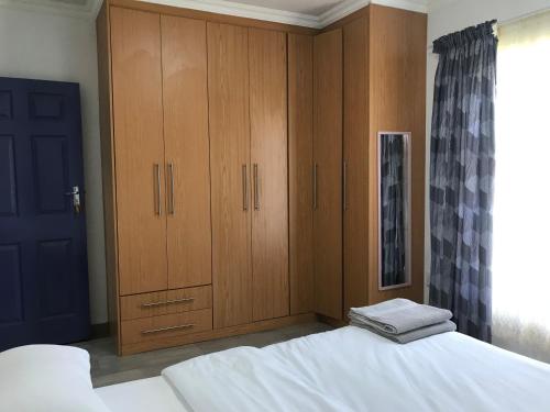 1 dormitorio con 1 cama y armarios de madera en The Plum, en Louis Trichardt