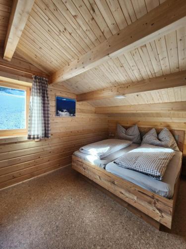 uma cama num chalé de madeira com uma janela em Lipphütte Top Lage mit traumhafter Aussicht em Rauris