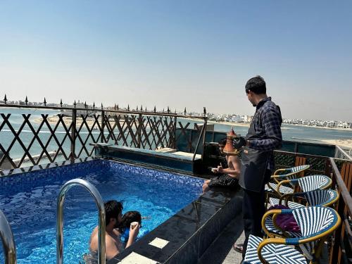 a man taking a picture of people in a swimming pool at منتجع اووه يامال البحري في الخيران OOh Yaa Mal in Al Khīrān