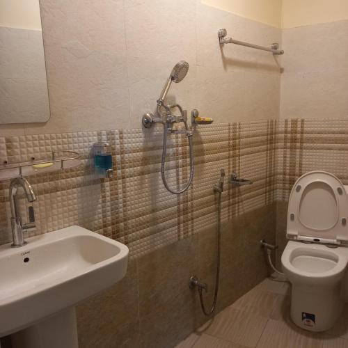 a bathroom with a shower and a toilet and a sink at KAJI HOME in Pātan