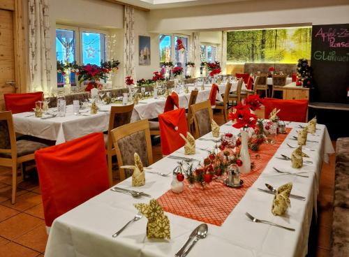 un comedor con mesas blancas y sillas rojas en Gasthaus - Pension Kärntnerhof, en Faak am See