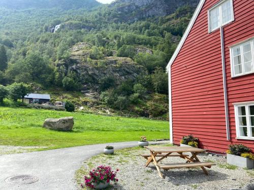 a wooden picnic table next to a red building at Brekke Gard Hostel in Flåm