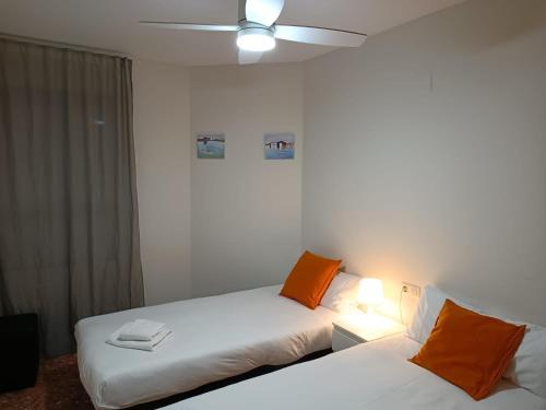 a room with two beds and a ceiling fan at APARTAMENTO CON PISCINA CERCA DE LA NUEVA FE. in Valencia