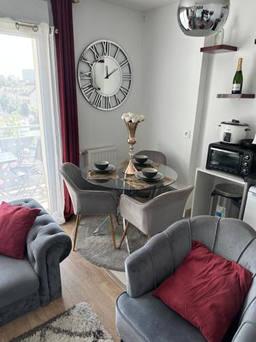 - un salon avec une table et une horloge murale dans l'établissement T2 proche stade de Frace Paris très calme design & Parking privé, à Bobigny