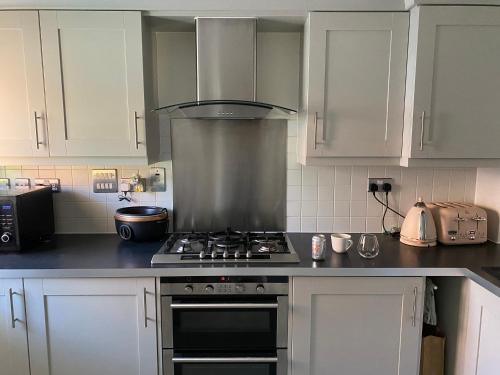 a kitchen with white cabinets and a stove top oven at Princes Risborough, Buckinghamshire, comfortable double room, quiet and central location in Buckinghamshire