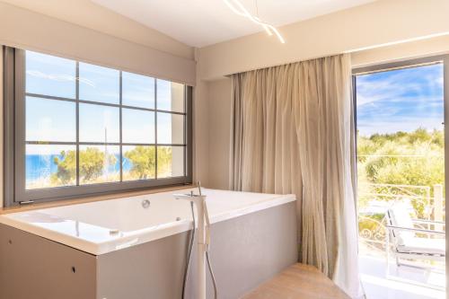 ein Bad mit einer Badewanne und einem großen Fenster in der Unterkunft Balcony Boutique Hotel in Planos