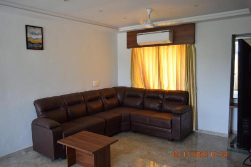 a brown leather couch in a living room with a table at LEELA BIZOTEL in Junagadh