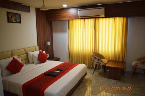 a hotel room with a bed with a red and white blanket at LEELA BIZOTEL in Junagadh