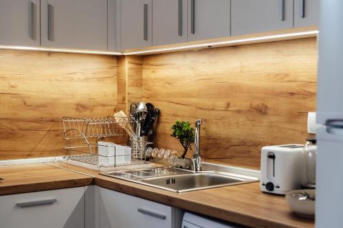 Una cocina con fregadero y una pared de madera. en VILLA MEDI boutique, en Sapareva Banya