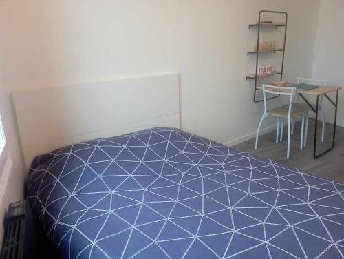 a bedroom with a blue bed and a table at LE KENAV - STUDIO A 300 M DU PORT in Locmiquélic