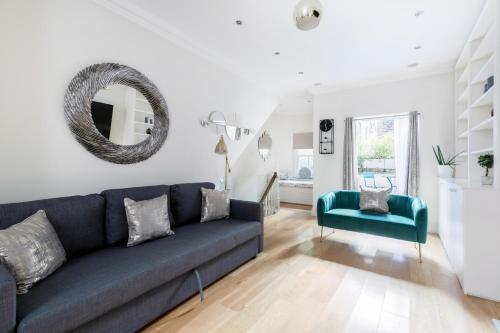 a living room with a blue couch and a mirror at Beautiful 4 Bedroom House near Paddington Station in London