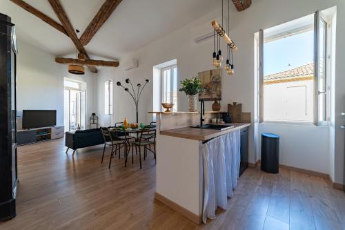 une cuisine et un salon avec des murs blancs et du parquet dans l'établissement La Cathédrale de Bois, à Nîmes