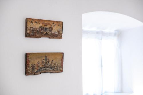 two pieces of art hanging on a wall next to a window at MEŽNARIJA Radovljica in Radovljica