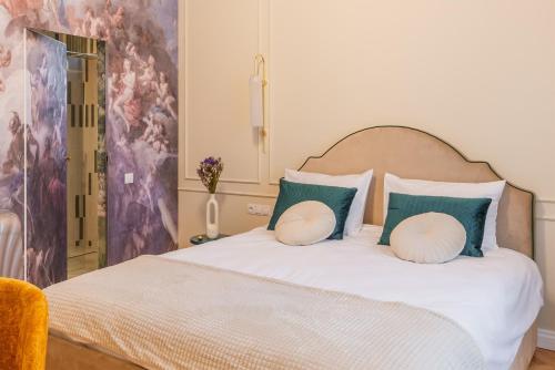 ein Schlafzimmer mit einem weißen Bett mit grünen und weißen Kissen in der Unterkunft Little Heaven Apartments in Sibiu