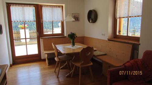 a living room with a table and chairs and windows at Kellnerhof in Nova Levante