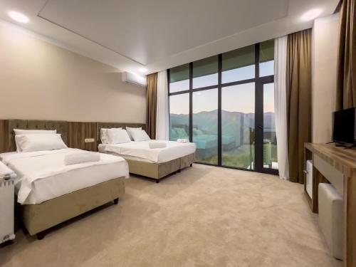 a hotel room with two beds and a large window at Chateau Milisi in Batumi