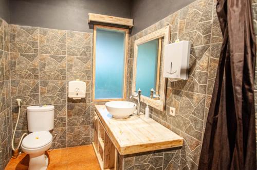 a bathroom with a sink and a toilet and a window at Kubuku Eco Dive Lodge and Yoga in Pemuteran