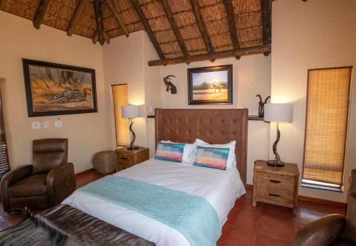 a bedroom with a bed and a chair in it at Ilanga Safari Lodge - Welgevonden Game Reserve in Vaalwater