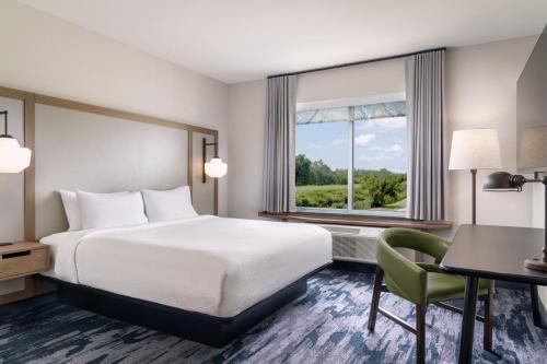BrooklynにあるFairfield Inn & Suites by Marriott Cleveland Tiedeman Roadのベッド、デスク、窓が備わるホテルルームです。