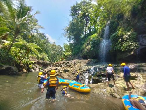 a group of people in the water near a waterfall at Aksha Riverside Ubud in Tampaksiring