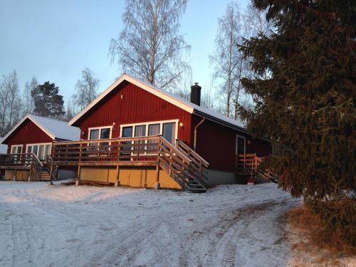 una casa roja con nieve en el suelo delante de ella en Siljan Utsikt Semesterhus, en Sjurberg