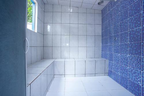 a white tiled bathroom with a shower with a window at Pousada Villa Blu Maresias in Maresias