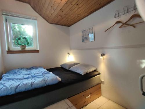 1 dormitorio con cama y ventana. en Kinderfreundliches Ferienhaus Mit Groem Pool en Otterup