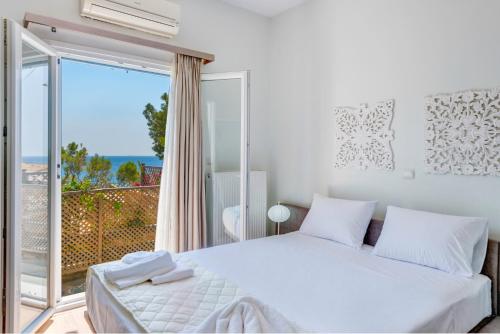 1 dormitorio con cama blanca y ventana grande en Villa Maria Fabrika Syros, en Vári