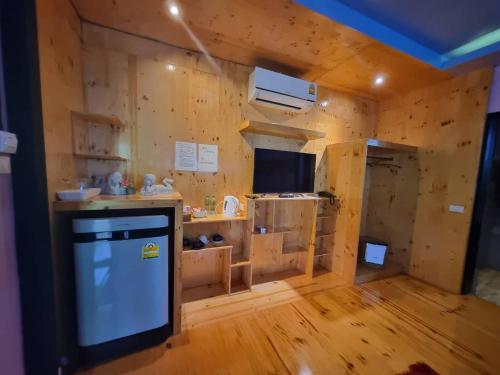 een kamer met houten wanden en een keuken met een televisie bij ปลายน้ำรีสอร์ท พรหมคีรี นครศรี ฯ Plainam Resort in Ban Khaek