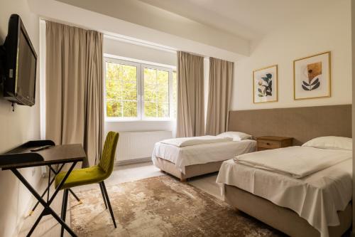 1 dormitorio con 2 camas, escritorio y TV en Monterai Resort en Poiana Brasov