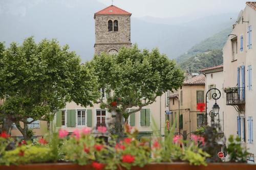 a building with a clock tower in a town with flowers at l'Espinet Vacances in Quillan