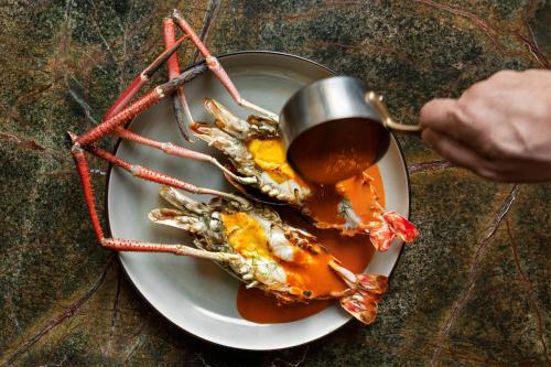 a plate of food with a crab with a cup of sauce at W Bangkok Hotel in Bangkok