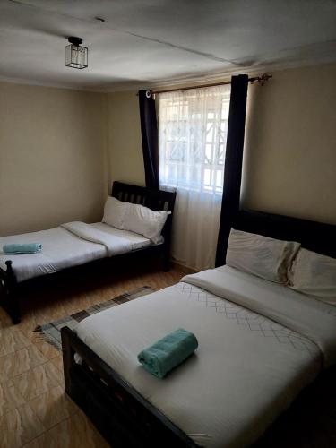 a room with two beds and a window at Jeda Homey Homes in Bomet