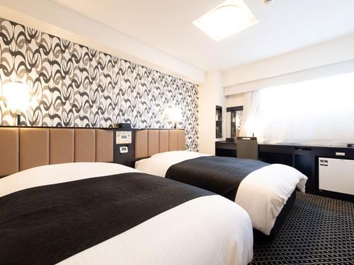 東京にあるアパホテル〈TKP東京西葛西〉のベッド2台と壁が備わるホテルルームです。